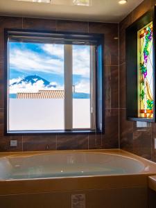 a bath tub in a bathroom with a window at Villa Ensoleille in Fujikawaguchiko