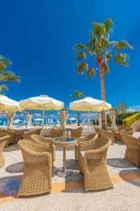 卡尼奧提的住宿－Elinotel Apolamare Hotel，海滩上一组桌椅和遮阳伞