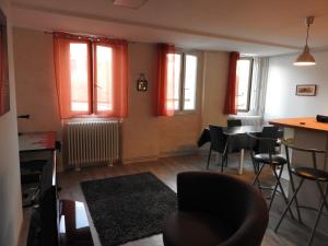 een woonkamer met een tafel, stoelen en ramen bij Appartement hyper centre ville au calme in Besançon