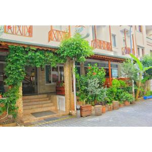a building with a bunch of potted plants in front of it at Rain Hotel in Kizkalesi