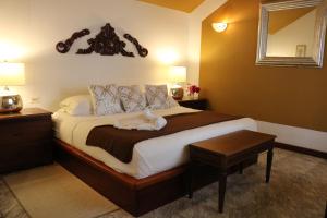a bedroom with a bed, chair, table and lamp at Villa Boscardi in Belize City