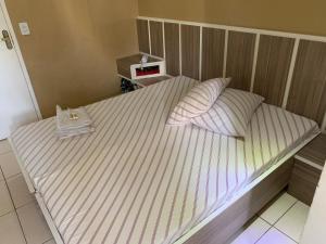 a bed with pink and white striped sheets and pillows at HOTEL FLOR DO AMAZONAS (ADULTS ONLY) in São Caetano do Sul