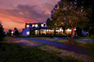 a building at night with purple flowers in front of it at Golden Pebble Hotel in Wantirna