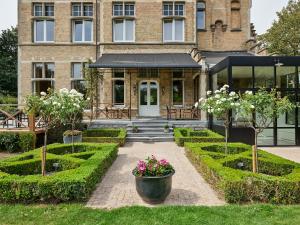 a garden in front of a building with trees and flowers at Boutique Hotel Ter Wallen in Izegem