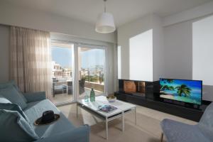 Una sala de estar con un sofá y un televisor. en Gras Houses - Near to sandy beach, en Agia Pelagia