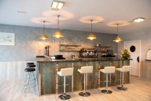 a kitchen with a bar with white bar stools at Hotel Vilaseco in Chantada