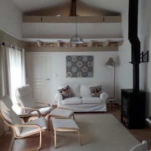 a living room with a white couch and chairs at Petit Gite Eymet in Eymet