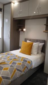 a bedroom with a bed with a yellow pillow at The Hatton Rooms in New Bedfont