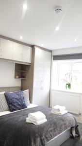 1 dormitorio con 1 cama con toallas en The Hatton Rooms en New Bedfont