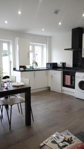 a kitchen with white cabinets and a table and a stove at The Hatton Rooms in New Bedfont