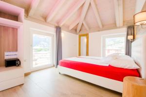 a bedroom with a red and white bed and windows at Casa Tosca - Holiday Home in Nago-Torbole