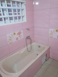 a pink bathroom with a tub and a window at MINI VILLA ROSE in Lomé