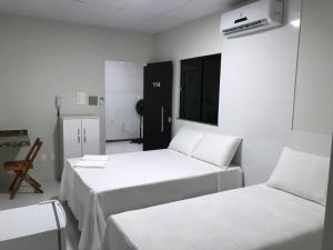 Duas camas num quarto branco com um frigorífico. em POUSADA PONTAL DO AGRESTE em Itabaiana