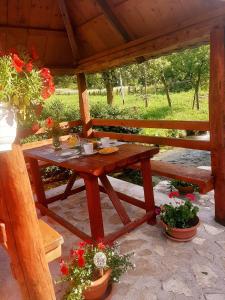 una mesa de picnic de madera en un pabellón con flores en Guest House Mila, en Plitvički Ljeskovac