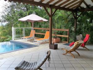 a patio with chairs and an umbrella and a pool at Villa Mahogany in Deshaies