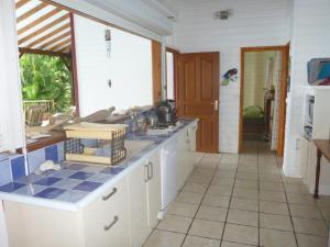 a kitchen with white cabinets and a blue tile floor at Villa Mahogany in Deshaies