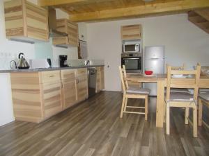 a kitchen with wooden cabinets and a table and chairs at Gîte Potimarron in Ancelle
