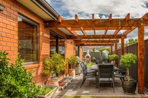 a patio with a table and chairs under a wooden pergola at 23onAlbert in Clyde