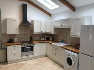 a kitchen with white cabinets and a washer and dryer at The Coach House in Cardiff