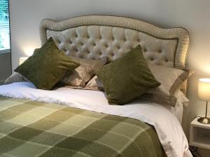1 dormitorio con 1 cama grande con almohadas verdes en The Coach House, en Cardiff