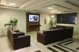 a waiting room with couches and a flat screen tv at Ouro Minas Plaza Hotel in Aparecida