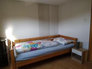 - un lit avec un cadre en bois et un oreiller dans l'établissement Ferienwohnung Gönnern - Marburg Biedenkopf mit 5 Zimmer - 2 Badezimmer, à Gönnern