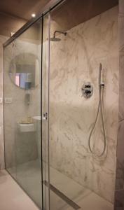 uma casa de banho com um chuveiro e uma porta de vidro em Scene Suites Apartments em Catânia