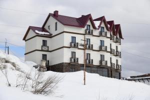 a large white building on top of a snow covered hill at Hotel Ereto in Gudauri