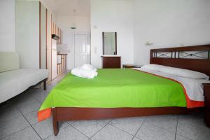 a bedroom with a large bed with a green blanket at Spiros Studios in Parga