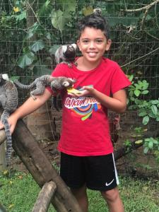 a young boy holding a lizard on his shoulder at Jabaquara Beach Resort in Paraty