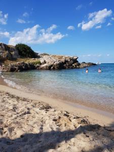 a beach with people swimming in the water at Casa Arco della Chicca in Monopoli