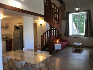 eine Küche und ein Wohnzimmer mit einem Tisch und einer Wendeltreppe in der Unterkunft Le Loft Du Chateau Du Roi in Cahors