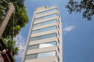 un edificio alto con ventanas de cristal en el lateral. en Suites Coben Apartamentos Amueblados en Ciudad de México