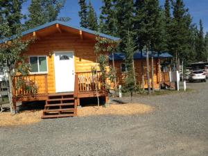 a log cabin with a white door and a porch at Tok RV Village and Cabins in Tok