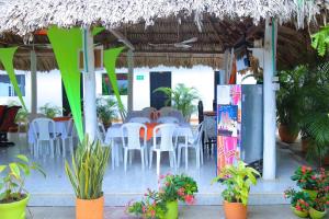 a restaurant with white tables and chairs and a straw roof at Casa Hotel Las Antillas in Tolú