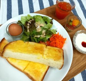 un plato blanco de comida con ensalada y pan en B&B Forest Shima, en Shima