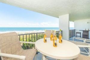 a table and chairs on a balcony with the ocean at Cape Winds in Cape Canaveral