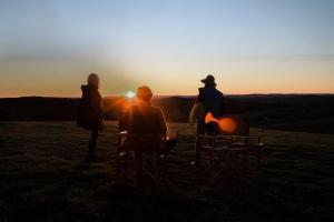 three people sitting in chairs watching the sunset at Rosewood Farmstay in Binda +4 photos