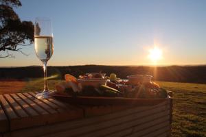 a table with a plate of food and a glass of wine at Rosewood Farmstay in Binda