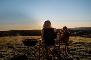 a woman and a man sitting in chairs next to a fire at Rosewood Farmstay in Binda