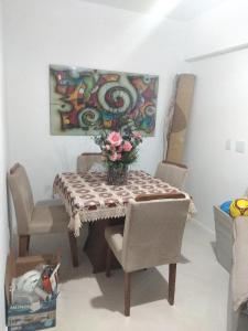 une table de salle à manger avec un vase de fleurs dessus dans l'établissement Apartamento Com Vista Para o Mar Com 2 Vagas de Garagem, à Arraial do Cabo