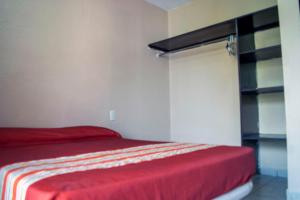 Schlafzimmer mit einem Bett mit einer roten Tagesdecke in der Unterkunft Isabel Suites in Zihuatanejo