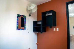 a room with an orange wall with a fan and a mirror at Isabel Suites in Zihuatanejo