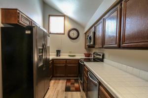 cocina con armarios de madera y nevera negra en Aspen Creek #306 Condo, en Mammoth Lakes