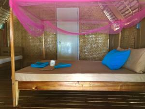 Cama con almohadas azules y dosel rosa en Modessa Island, en Roxas 24 fotos más