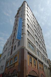 un edificio blanco alto con un letrero azul. en Beppu Station Hotel en Beppu