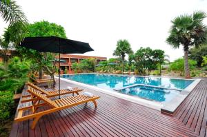 a pool with benches and an umbrella on a deck at Bagan Wynn Hotel in Bagan