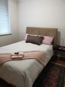 uma cama com almofadas cor-de-rosa e um cobertor em Apartment with a View em Perth