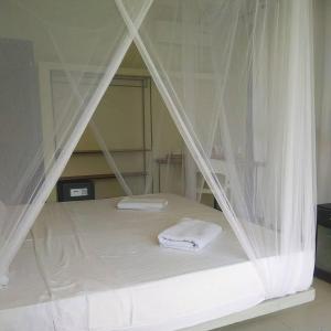 ein Bett mit weißen Vorhängen und zwei Handtüchern darauf in der Unterkunft Secret Garden Galle Fort in Galle