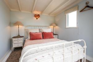 um quarto com uma cama branca e almofadas vermelhas em The Settlers Hut em Oneroa
